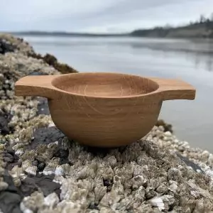 Handcrafted Scottish oak whisky quaich set on a rock overlooking the sea