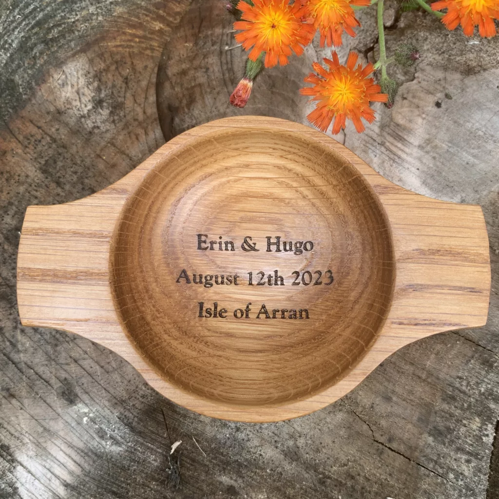 A unique handcrafted wooden oak wedding quaich engraved with names, location and dates of the happy couple