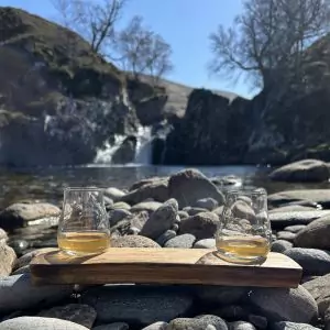 Oak whisky stave drink set with 2 spey tasting glasses set against the backdrop of a Scottish Highland waterfall